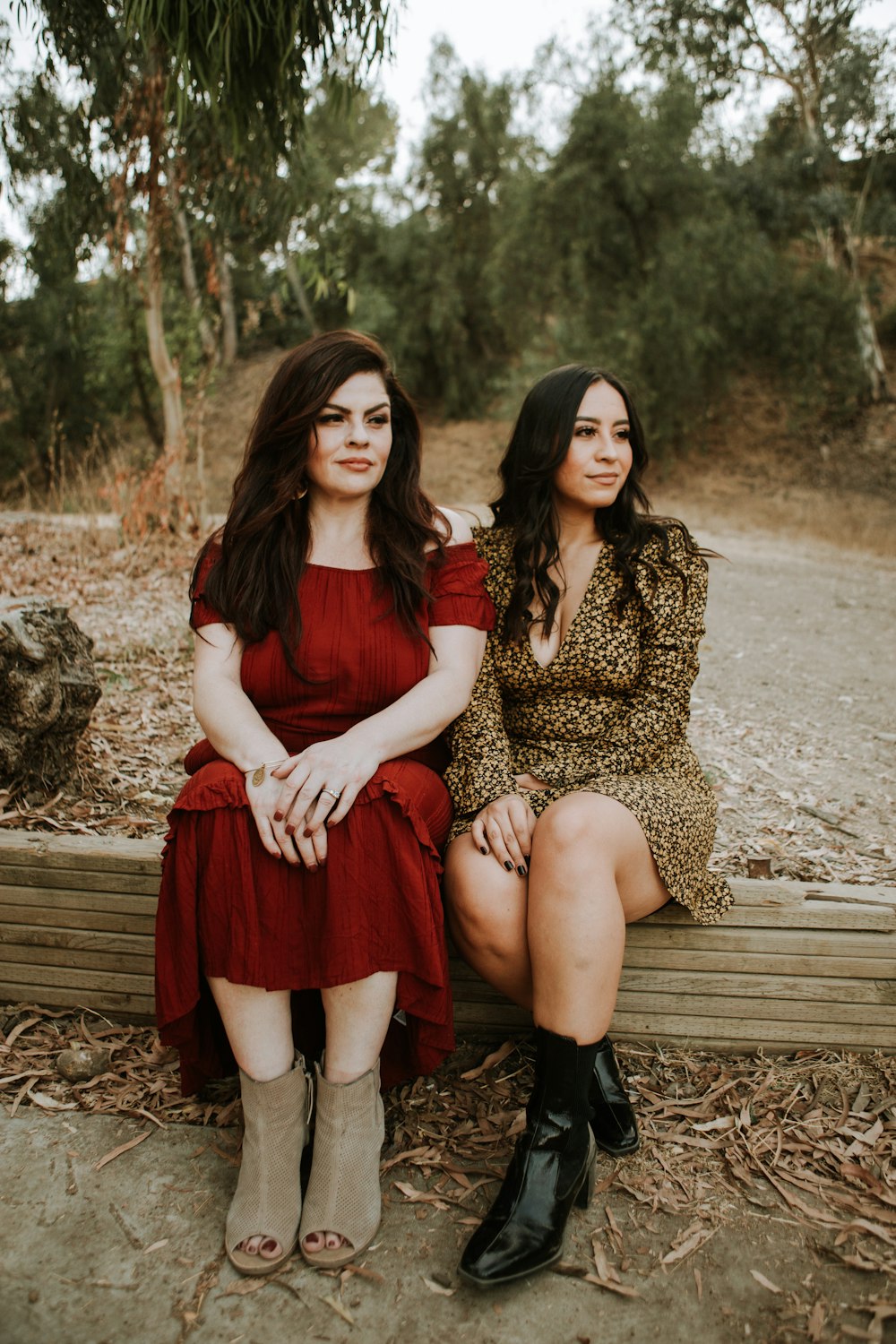 2 femmes en robe rouge assises sur un banc en bois brun