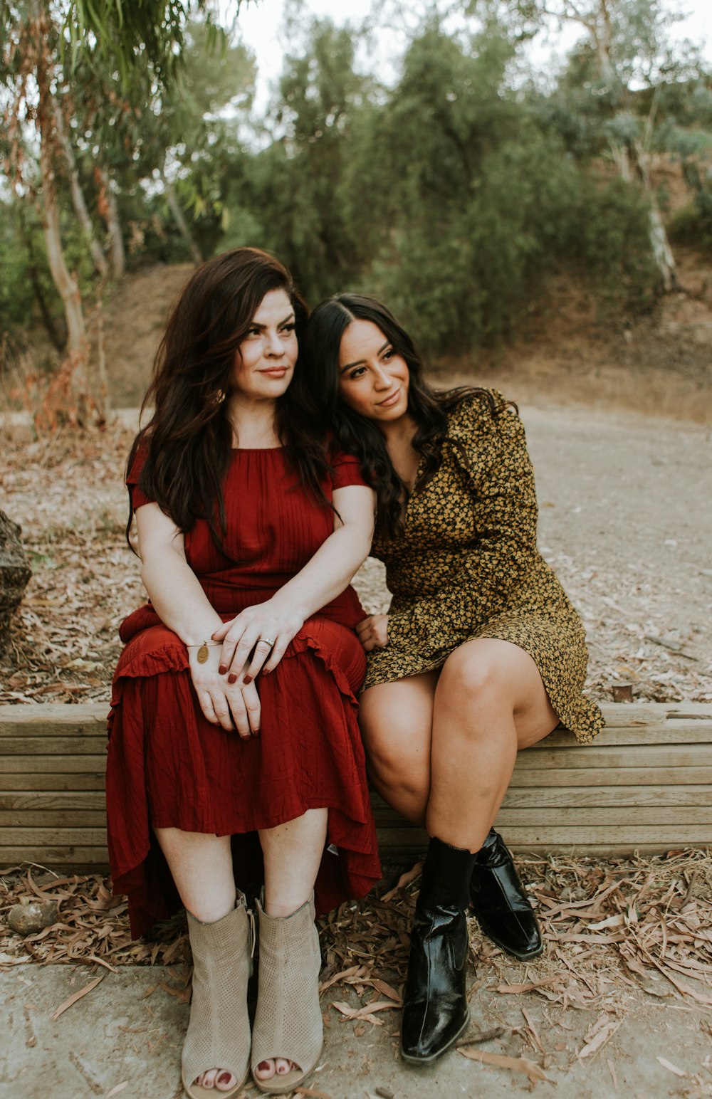 2 femmes assises sur un banc en bois brun