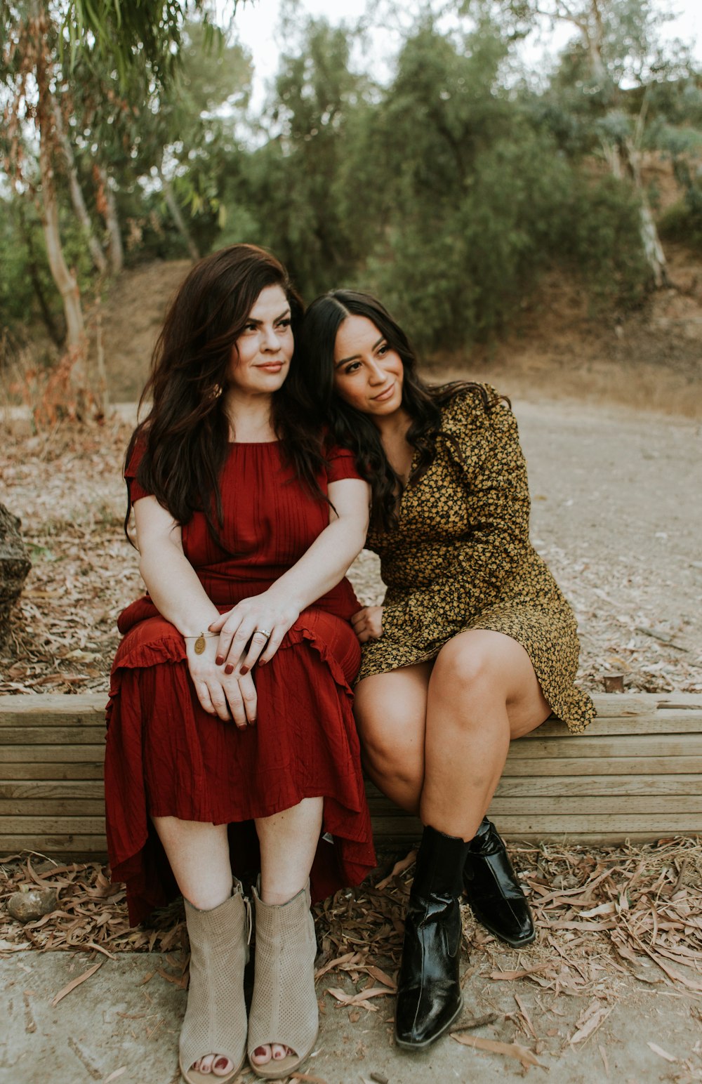 2 women sitting on brown wooden bench