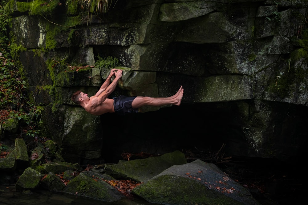 man in black shorts standing on rock