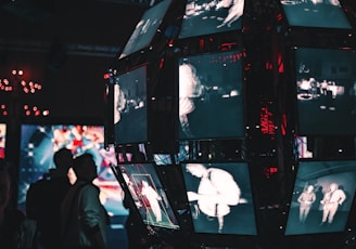 a group of people standing around a display of video screens