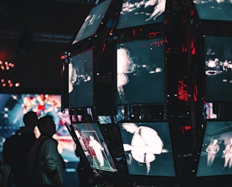 a group of people standing around a display of video screens