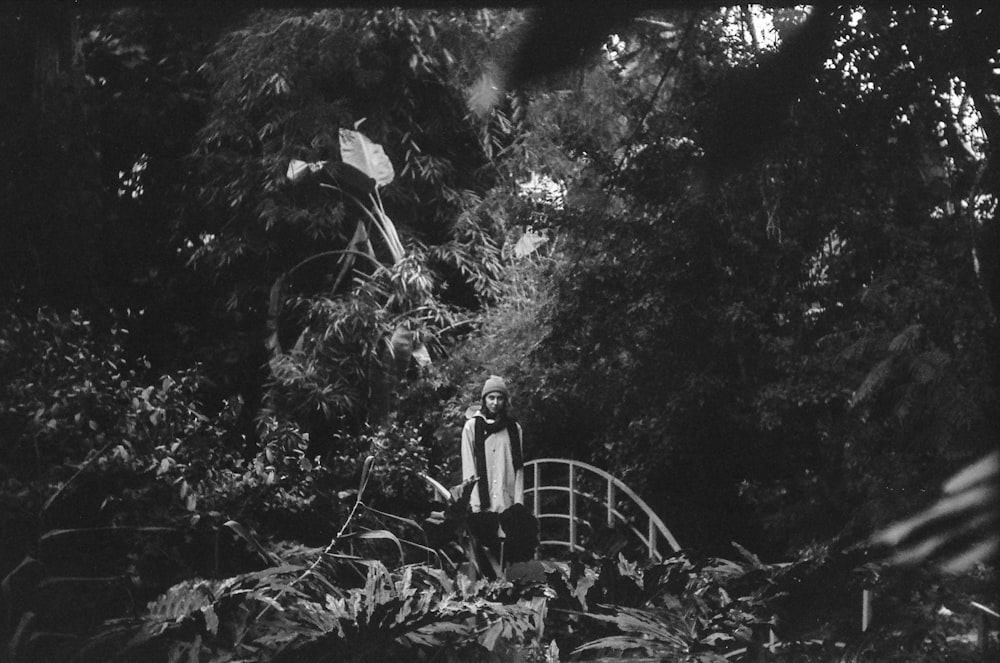 Mujer vestida de blanco de pie en el bosque en fotografía en escala de grises