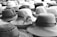 A collection of hats in various styles and patterns is displayed, featuring both light and dark shades. The intricate designs of the hats include woven textures and ribbon embellishments, creating an array of visual interest.