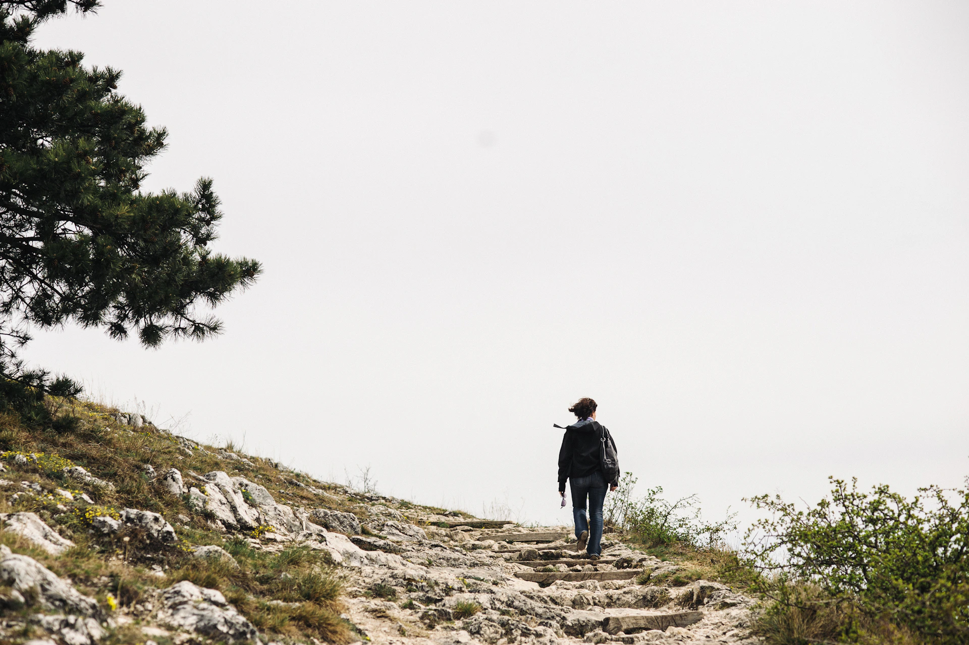 man in black jacket standing on gray rock during daytime