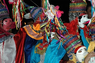 Colorful, sequined costumes and masks create a vibrant and festive scene, with bright ribbons and intricate patterns. The costumes are adorned with various textures and details.