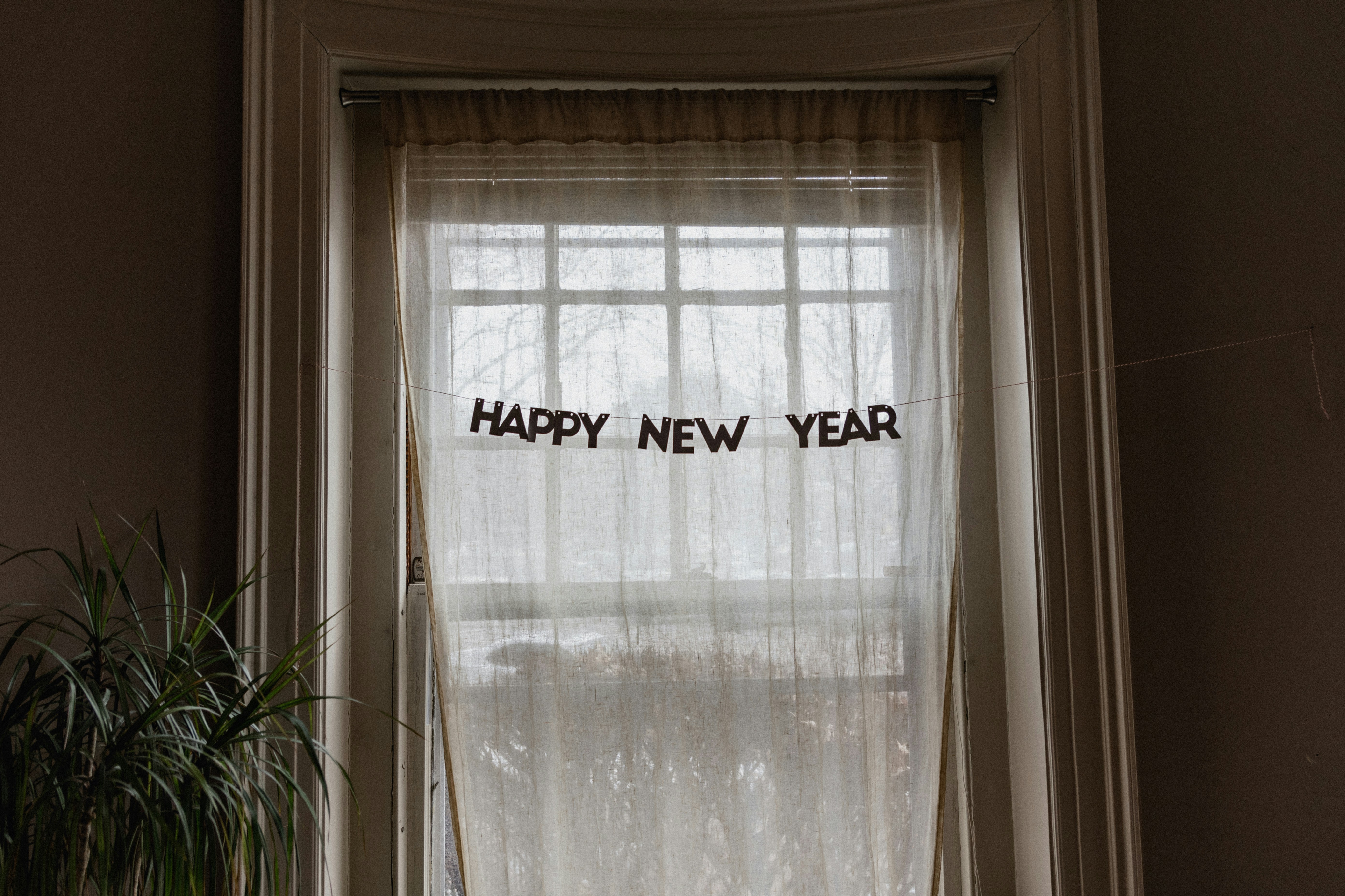 Happy New Year sign hanging in a curtained window