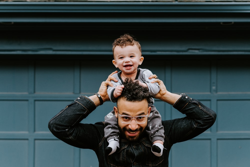 man in black leather jacket carrying boy in black leather jacket