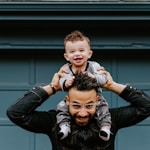 man in black leather jacket carrying boy in black leather jacket