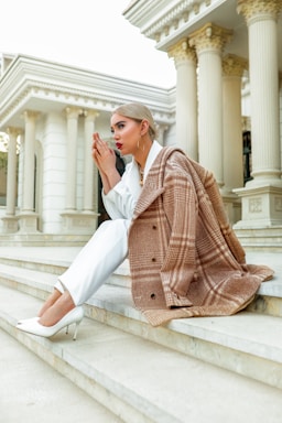 fashion photography,how to photograph woman in white pants and red and white plaid coat sitting on white concrete bench