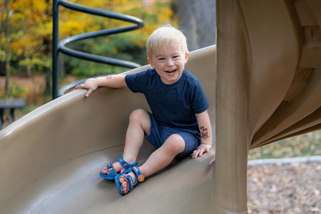 boy in blue crew neck t-shirt sitting on brown wooden stairs,