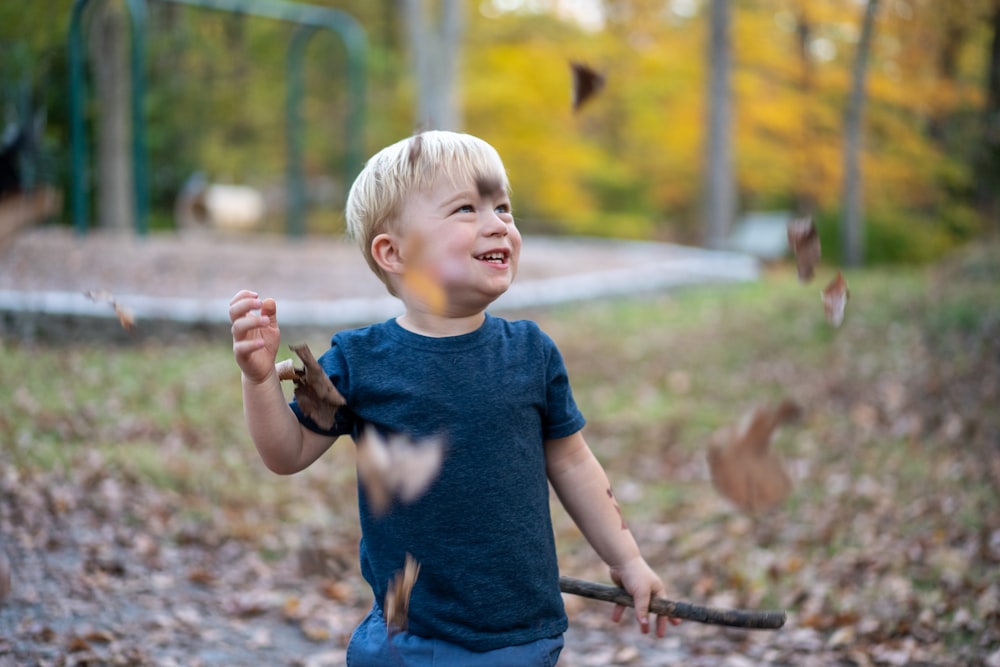 boy in blue crew neck t-shirt holding stick during daytime