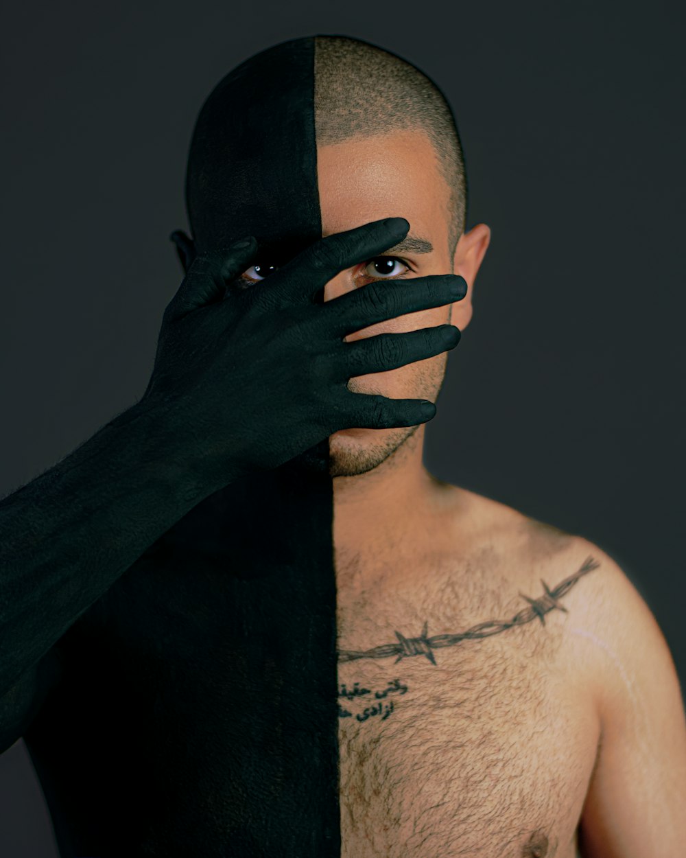 Hombre en topless con tatuaje negro en la cara