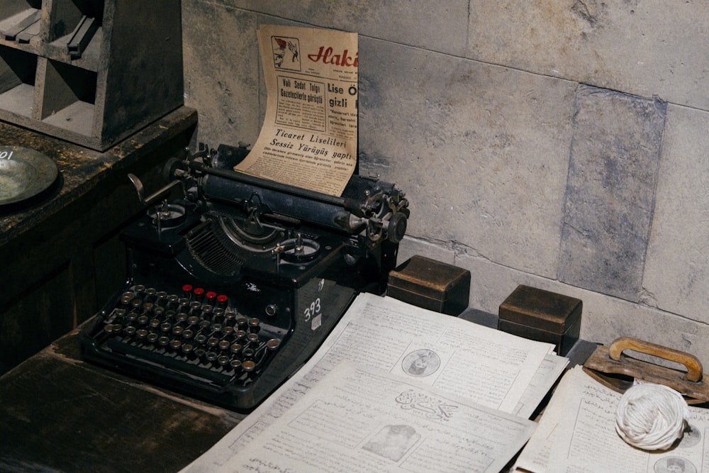black typewriter beside white printer paper