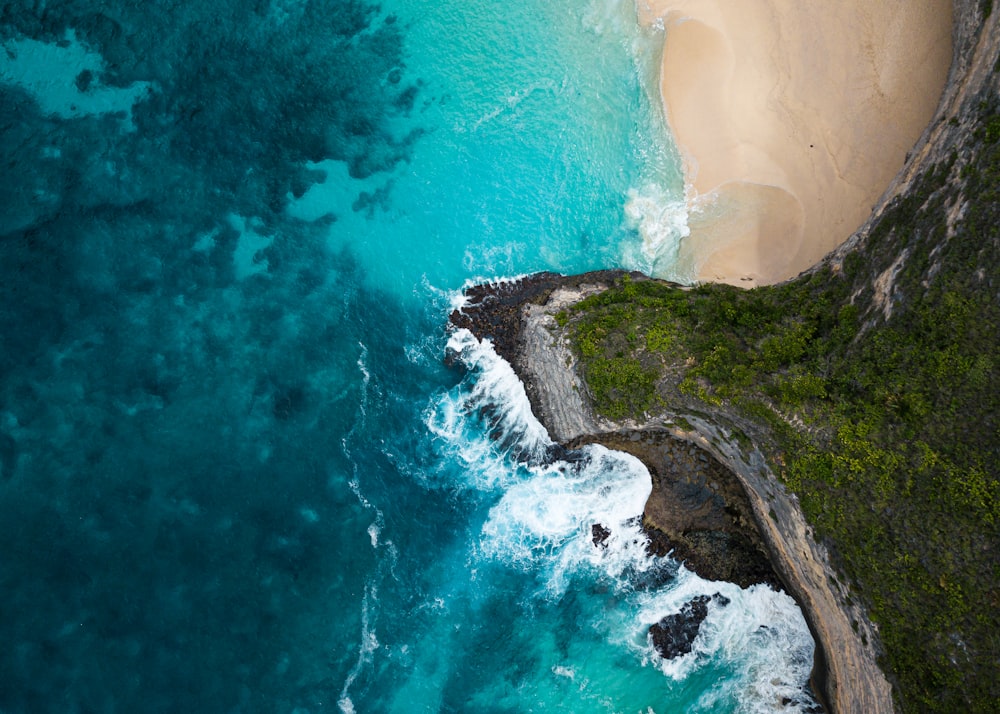 green and brown rock formation beside body of water during daytime