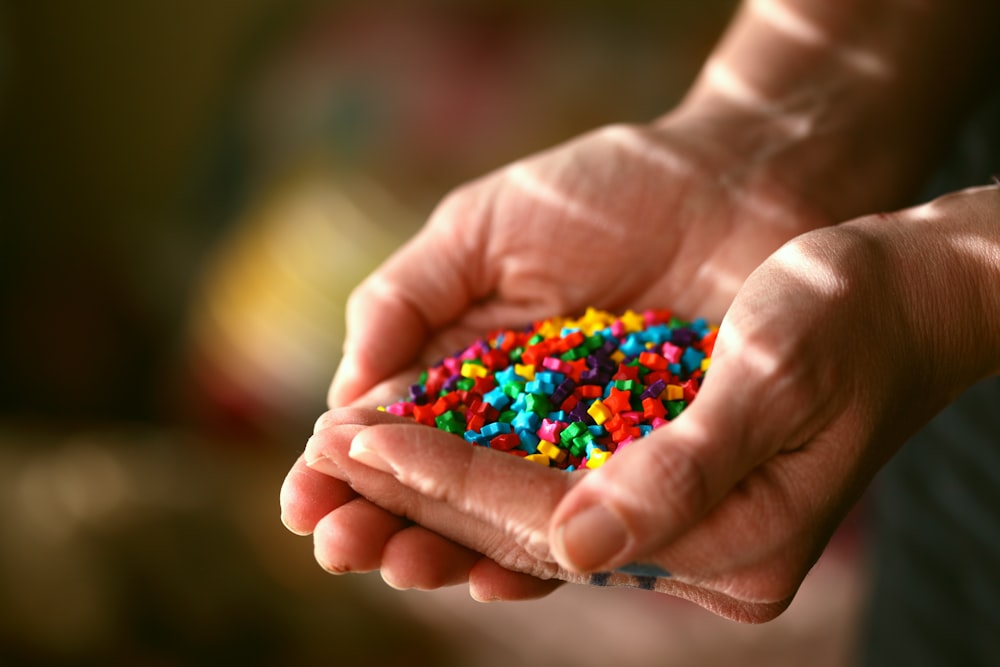 person holding multi colored beads