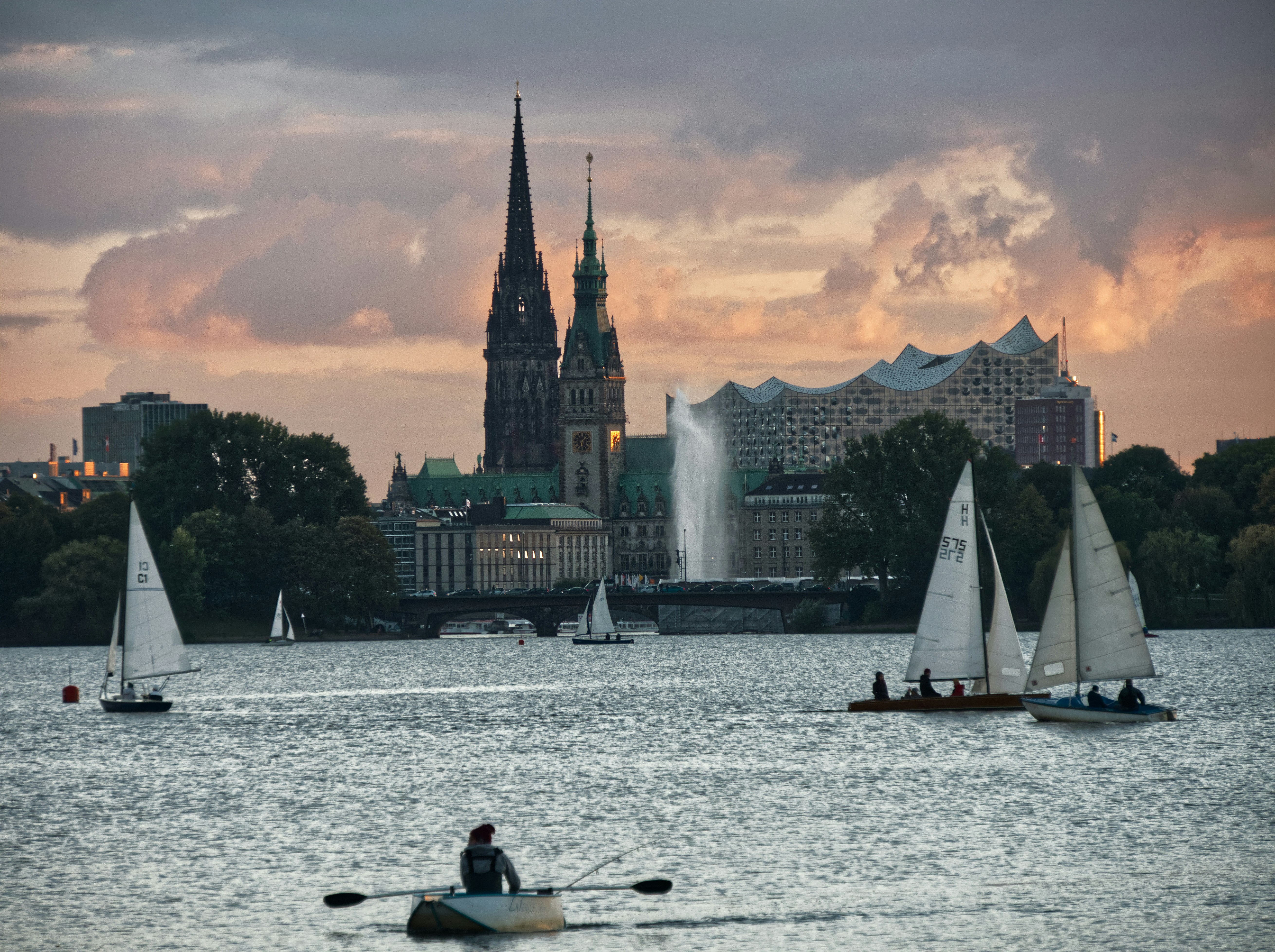 a group of sailboats in a body of water with a city in the background