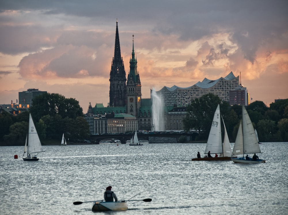 a group of sailboats in a body of water with a city in the background