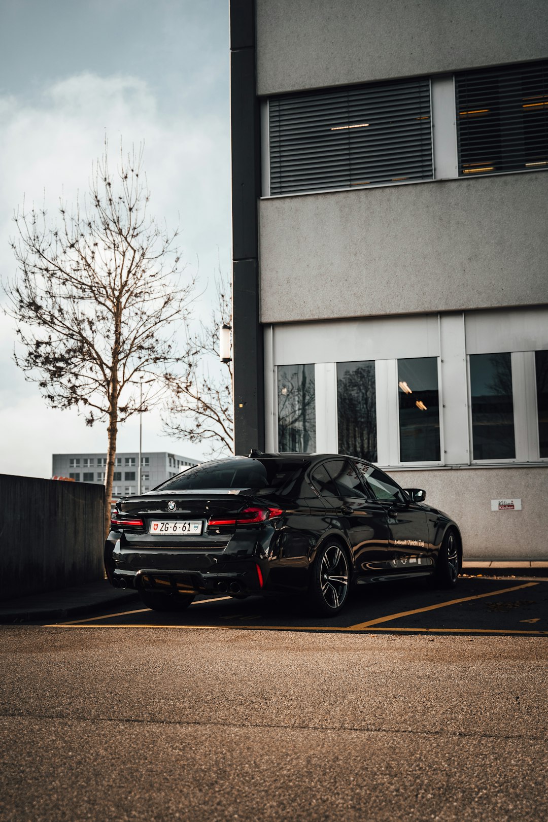 black sedan parked beside white building