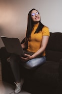 A cheerful senior woman sitting at a laptop, smiling as she follows an AI tutorial.
