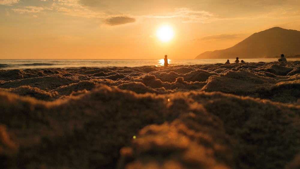 Silueta de la persona de pie en la orilla del mar durante la puesta del sol