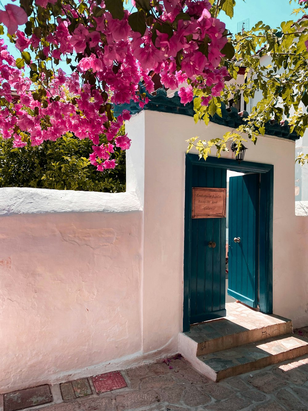 a doorway with a blue door and pink flowers