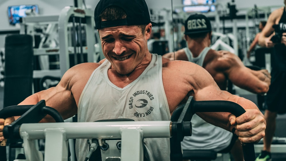 man in white tank top wearing black cap