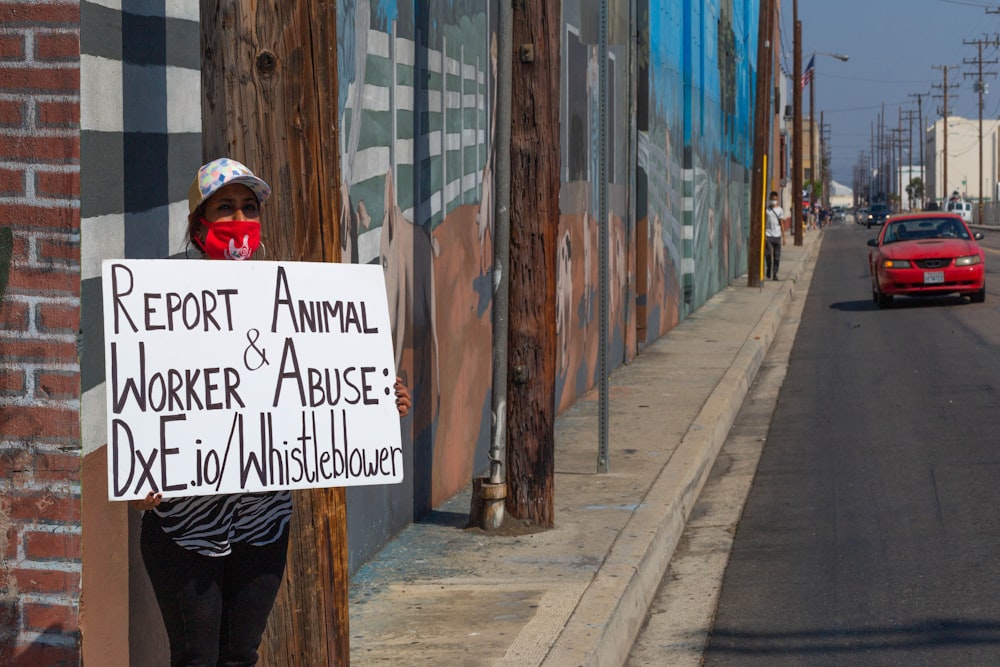 woman in black jacket and black pants walking on sidewalk with white and black signage