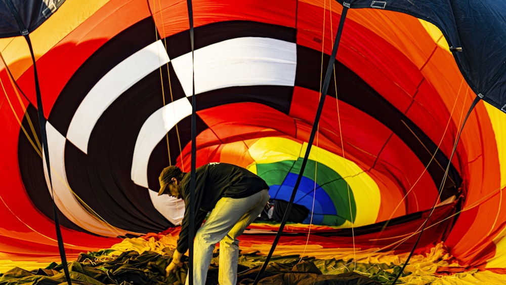 man in blue jacket and blue denim jeans lying on red and white hot air balloon