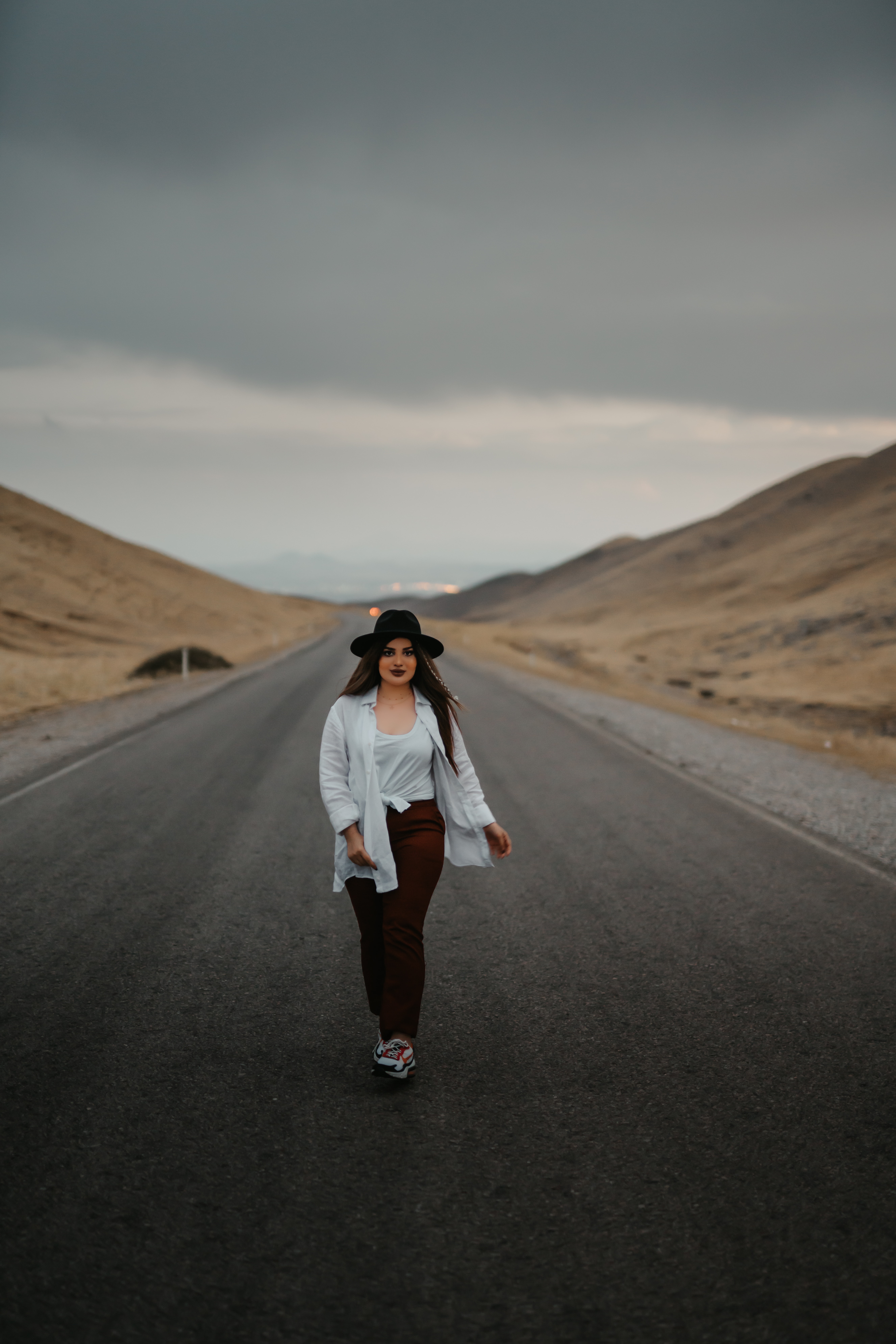 woman in white jacket and black pants standing on road during daytime