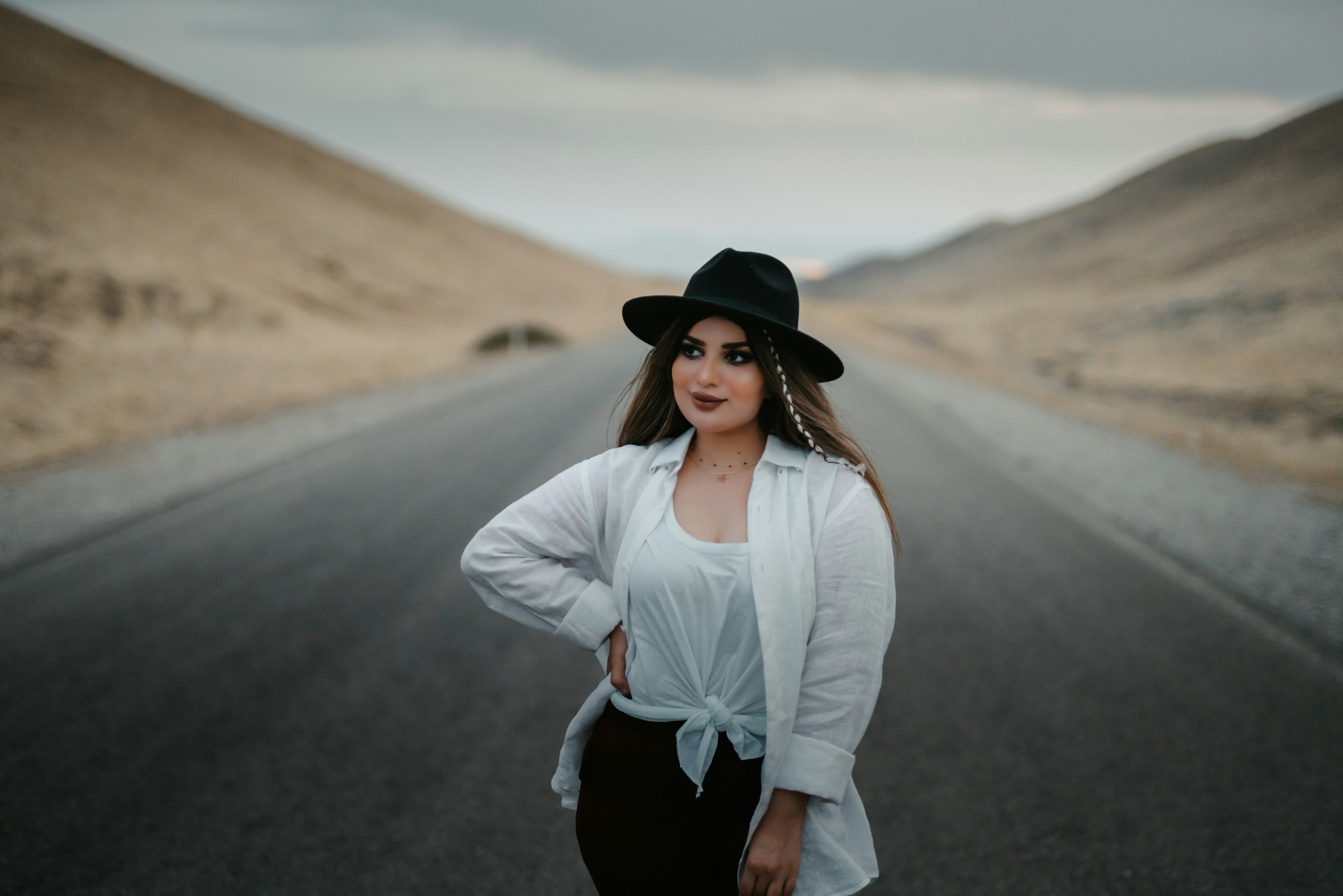 woman in white long sleeve shirt and black skirt standing on road during daytime