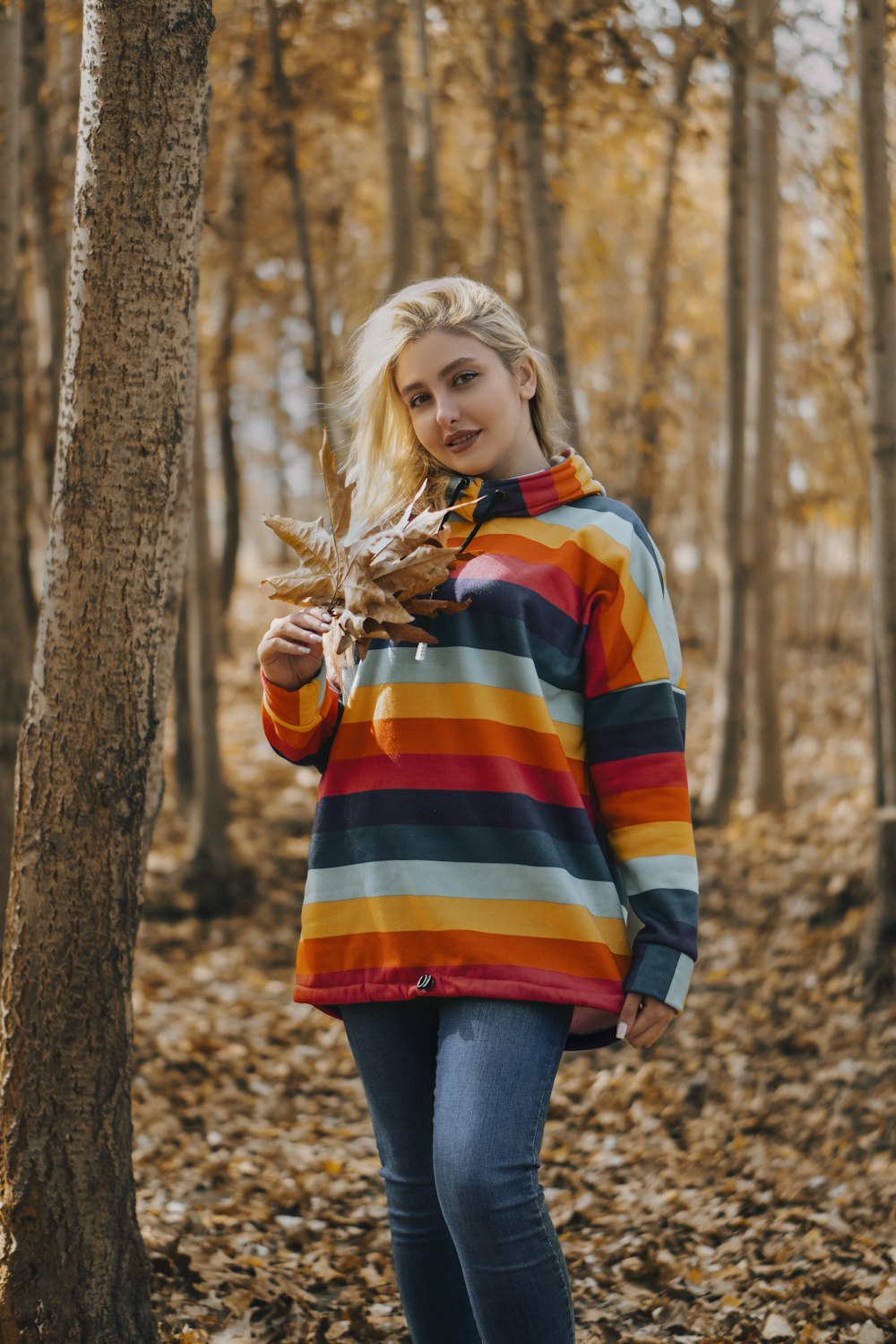 woman in orange and blue striped long sleeve shirt and blue denim jeans standing beside brown