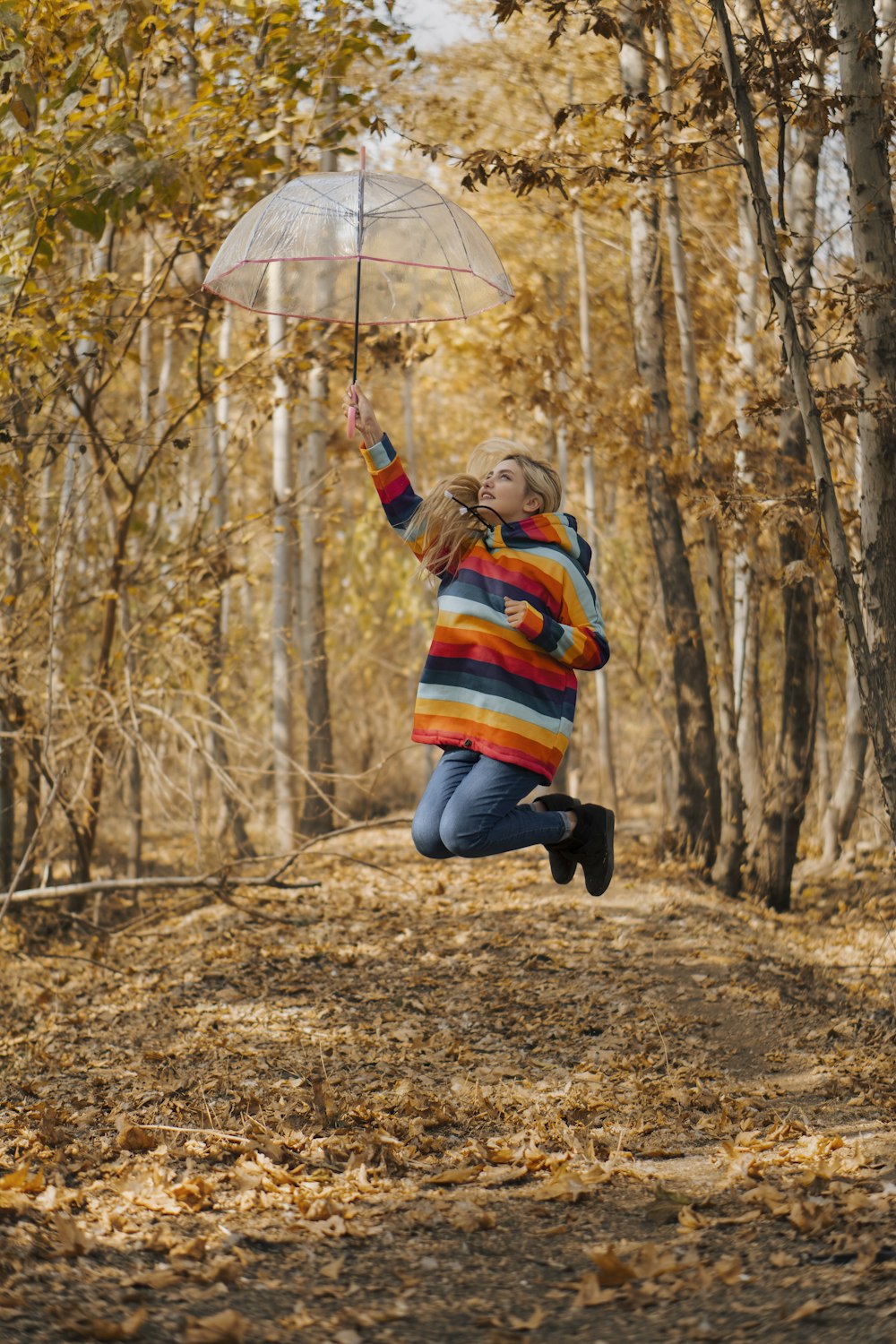 girl in blue and red striped long sleeve shirt and black pants holding umbrella