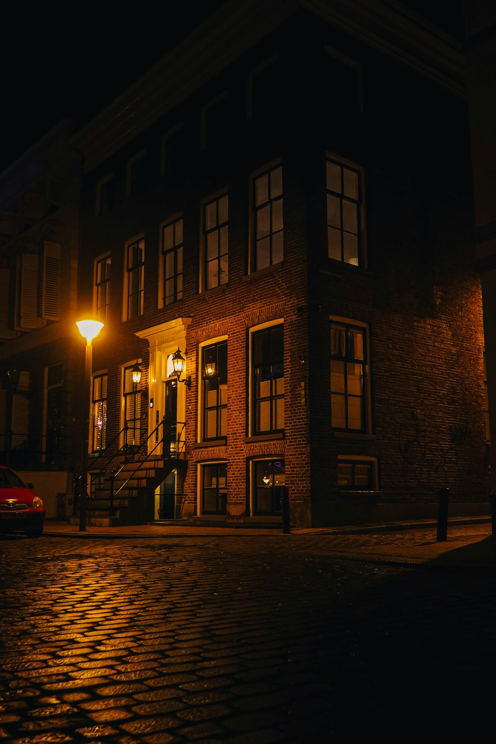 red car parked beside brown concrete building during night time