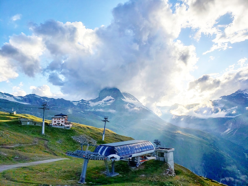 white and blue picnic table on green grass field near mountain under white clouds during daytime