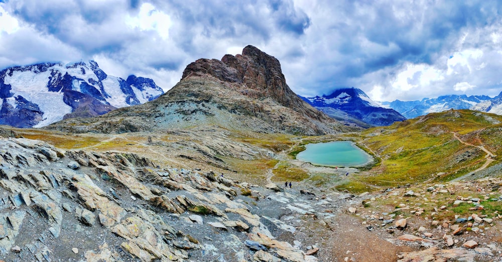 blue lake in the middle of rocky mountains under white clouds and blue sky during daytime