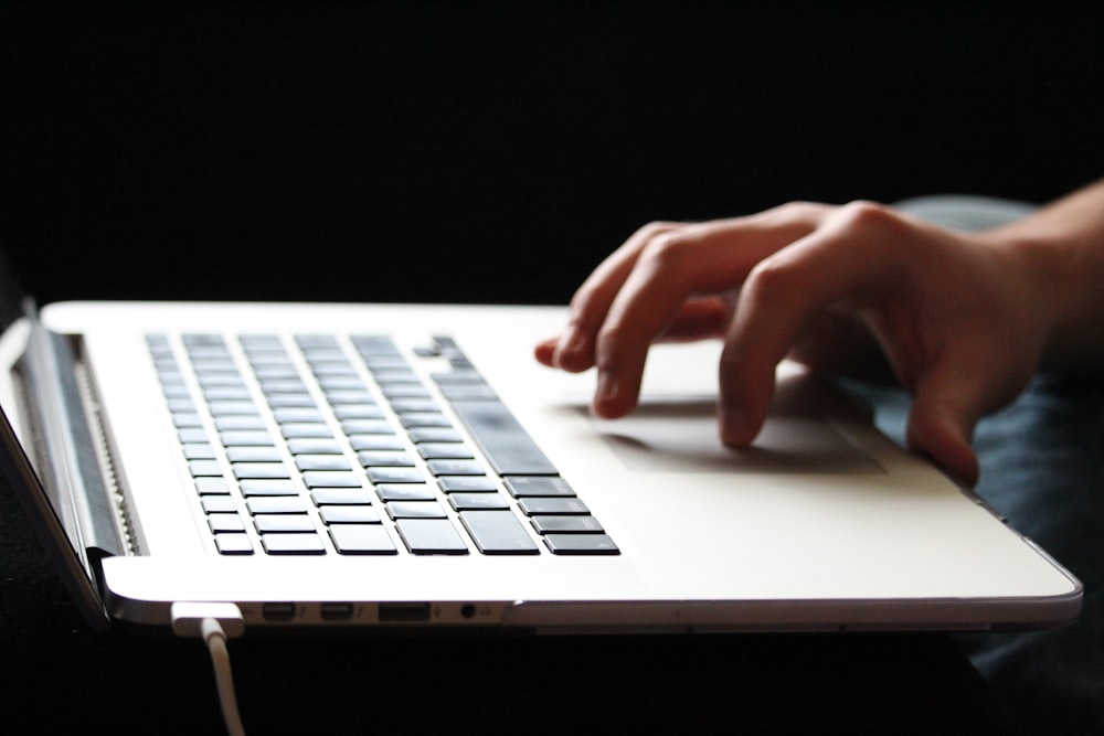 Persona usando MacBook Pro en una mesa de madera marrón