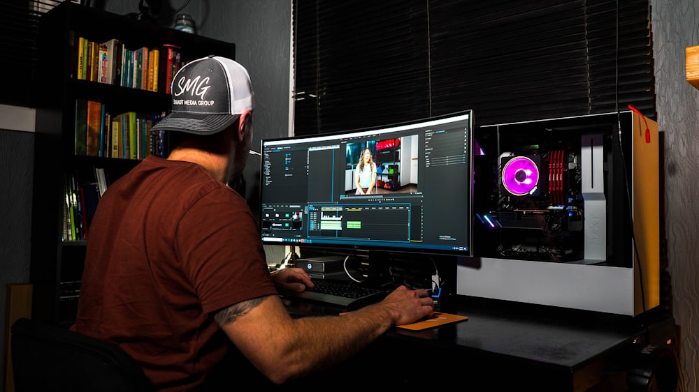 man in red t-shirt sitting in front of computer