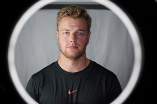 Man standing in the center of a ring light and creating content for a trending hashtag to get famous on TikTok.