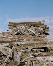A friendly Scrap That Services team member removing old wooden deck boards in a sunny backyard.