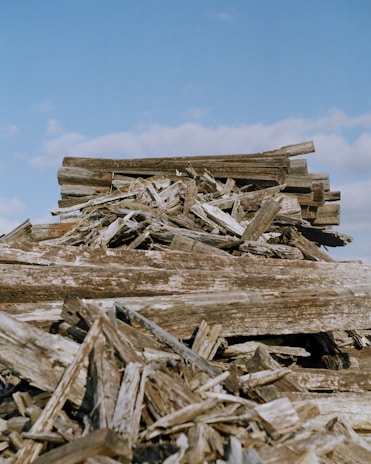 A friendly Scrap That Services team member removing old wooden deck boards in a sunny backyard.