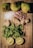 A flat lay of fresh ingredients on a wooden surface. The top row features three whole pears. Below them are cubes of sugar and a cluster of dried rosebuds. In the middle, there are pieces of fresh ginger root. The lower part of the composition shows a bunch of fresh mint leaves, and two halves of a lemon are positioned at the bottom.