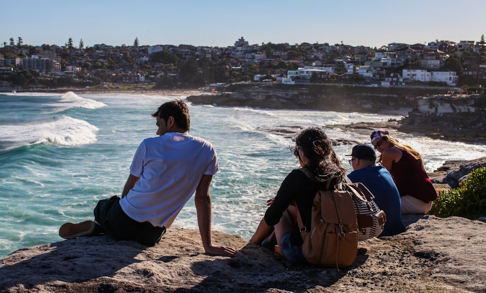 people sitting on brown rock near sea during daytime
