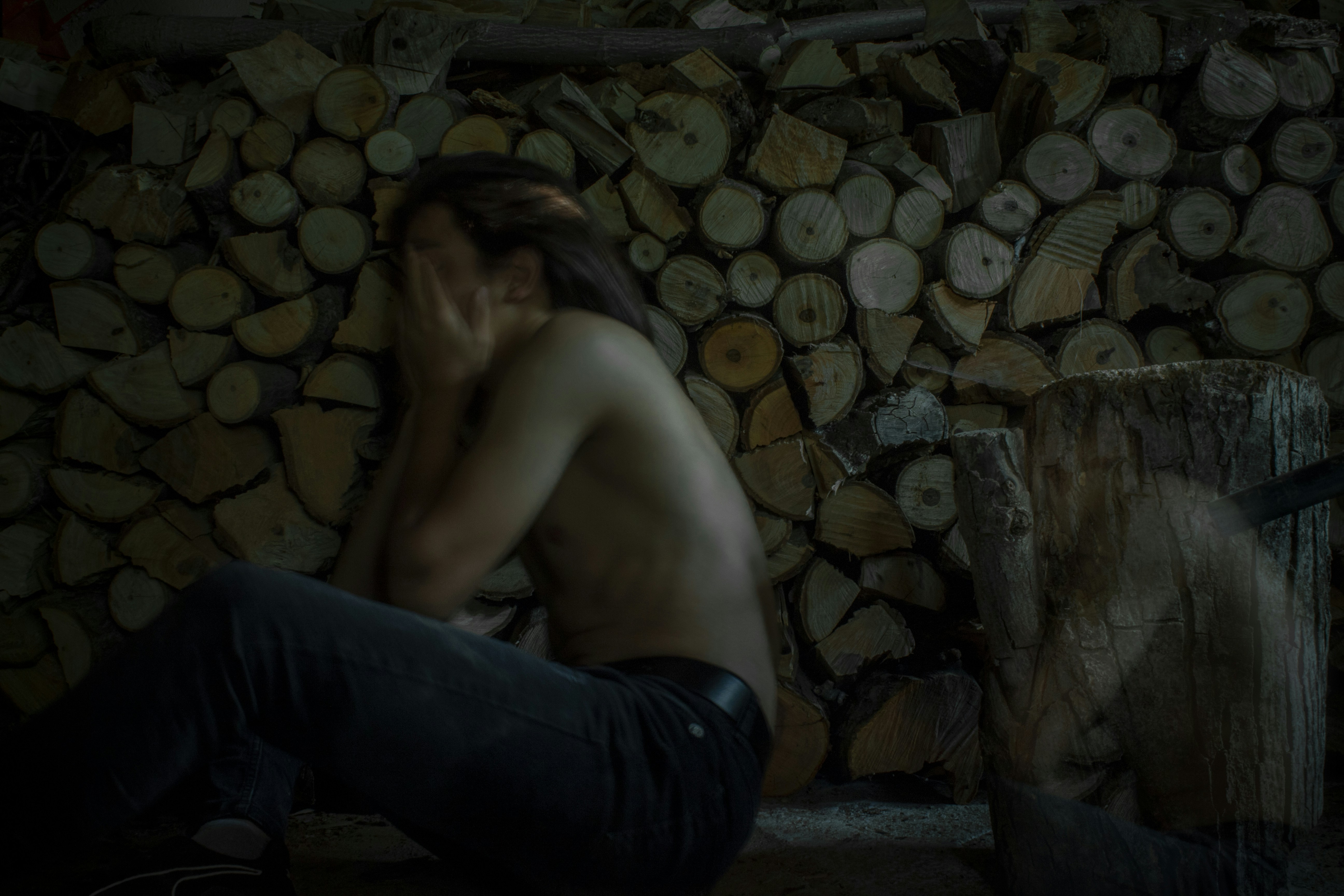 topless man in black pants sitting on concrete floor