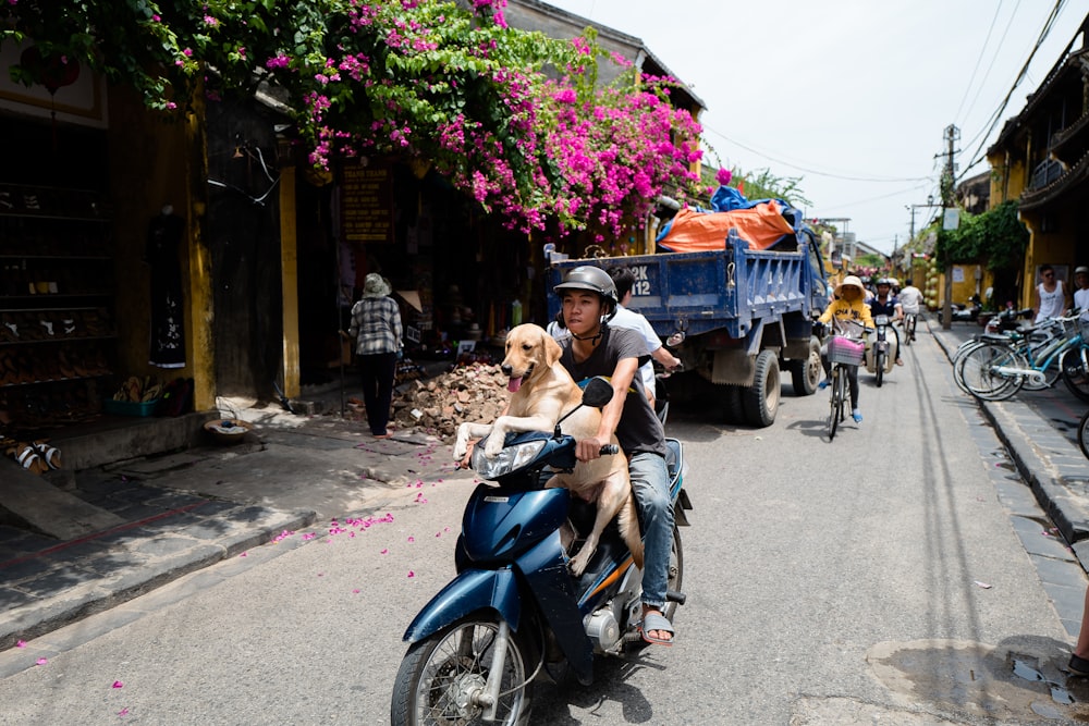 woman in black tank top riding blue motor scooter