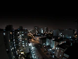 A nighttime cityscape with electric cars quietly cruising under streetlights.
