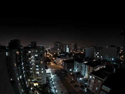 A nighttime cityscape with electric cars quietly cruising under streetlights.