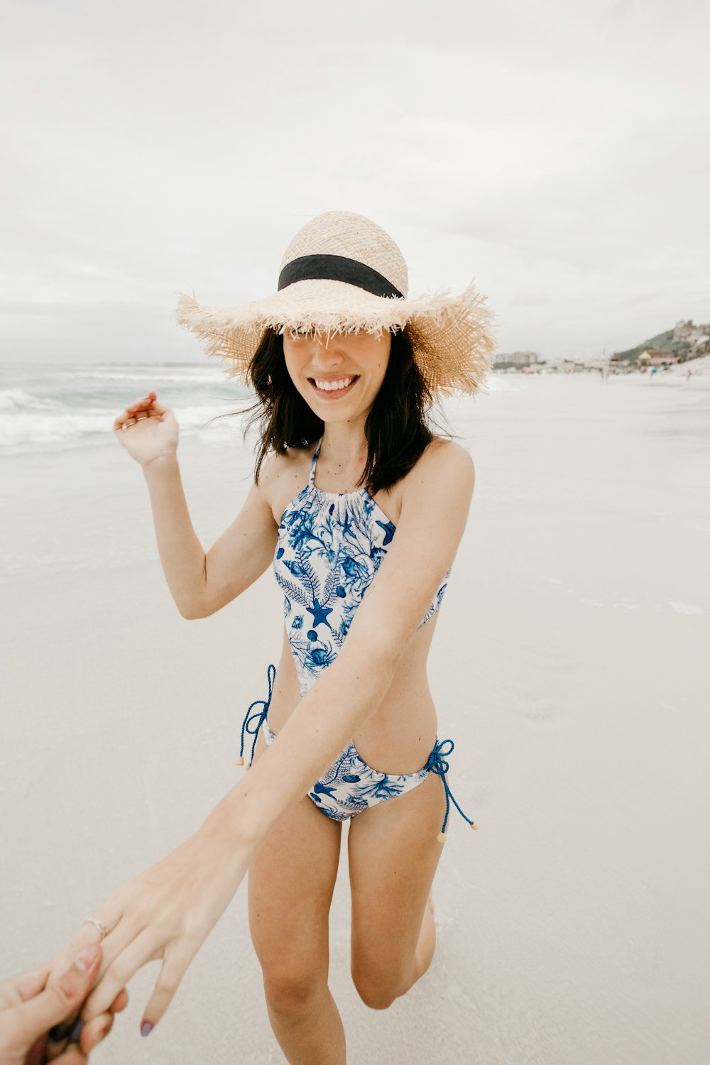 woman in blue and white floral bikini wearing brown straw hat standing on beach during daytime
