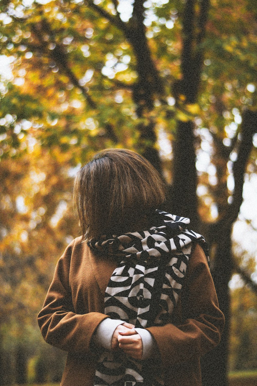 woman in brown jacket with black and white scarf