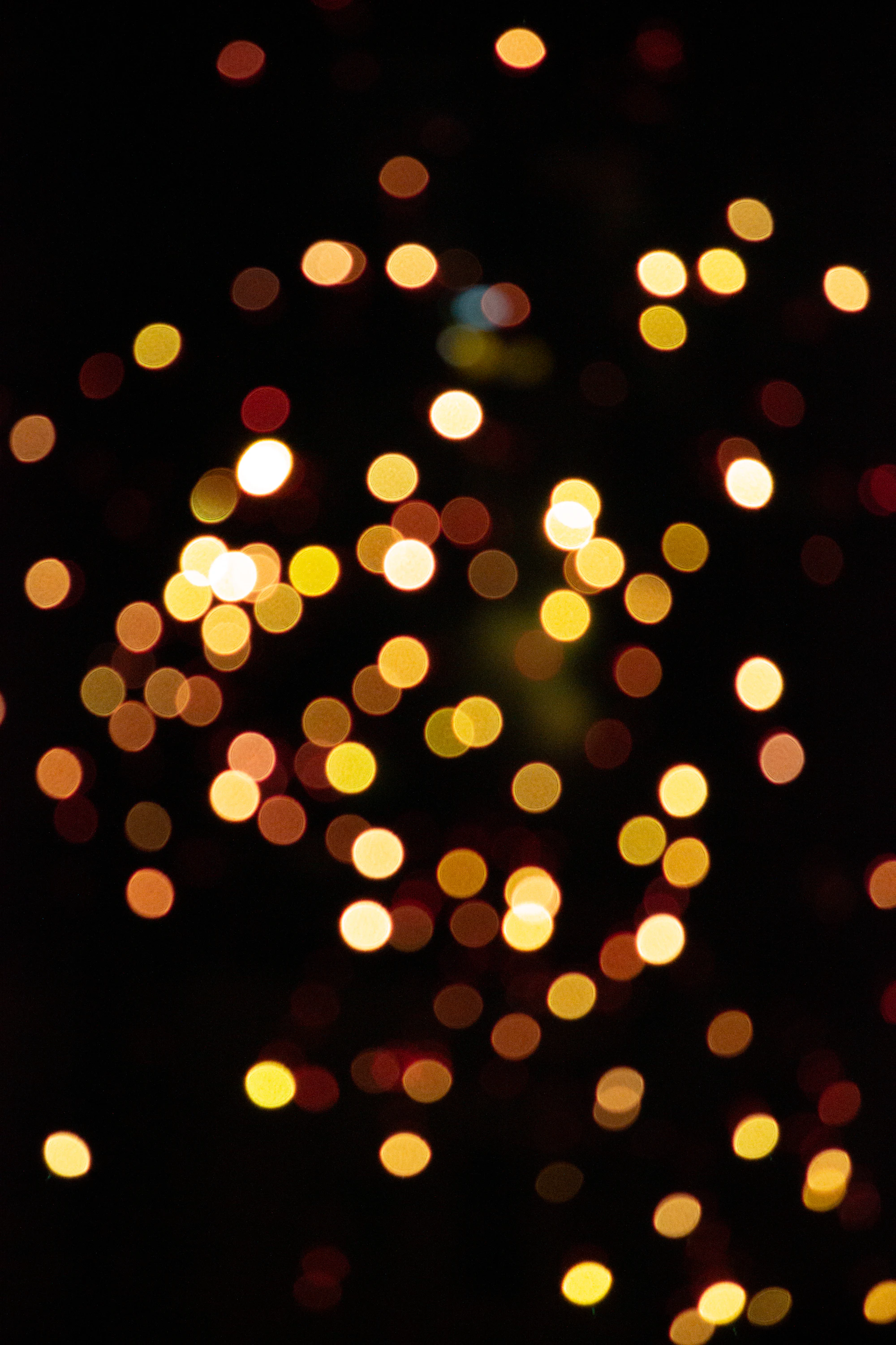 A haze of blurred, out-of-focus golden bokeh lights against total darkness